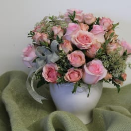 Pink rose bouquet in a white vase with a gray ribbon