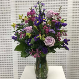 Mixed bouquet of purple and pink flowers in a glass vase