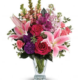 Pink lilies and roses arranged in a clear glass vase