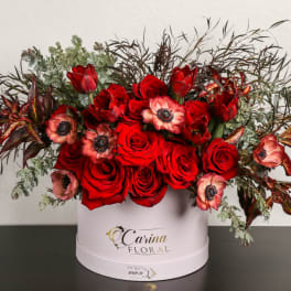 Red roses and pink anemones in a white hatbox