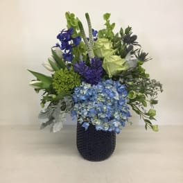 Blue hydrangeas and green roses in a dark vase