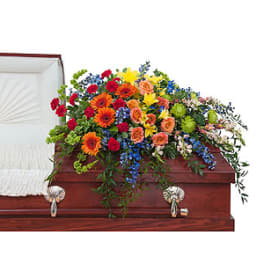 Colorful casket spray with mixed flowers on a wooden casket
