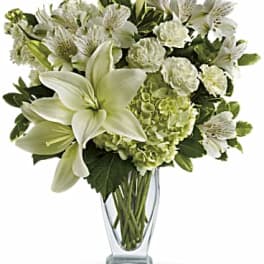 White lilies and green hydrangeas in a clear glass vase