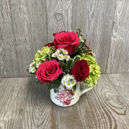 Pink and red roses with white daisies in a floral mug