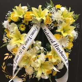 Yellow and white funeral wreath with ribbon tribute