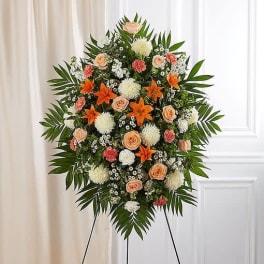 Standing floral spray with peach roses, orange lilies, and white blooms