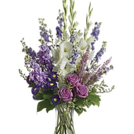 Tall bouquet of purple and white flowers in a clear glass vase