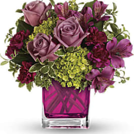 Pink roses and purple flowers in a square glass vase