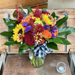 Colorful mixed bouquet in a glass vase with a plaid ribbon