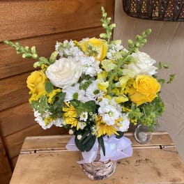 Yellow and white mixed flower arrangement in a birch-style container with a lavender ribbon