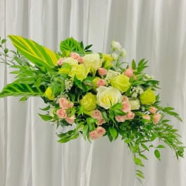 Large floral arrangement with yellow and pink roses and lush greenery