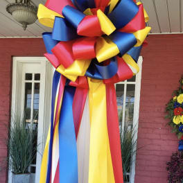Large decorative ribbon bow in red, blue, and yellow hanging on a doorway