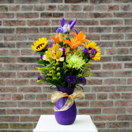 Colorful bouquet in a purple vase with a ribbon bow