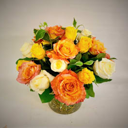 Bouquet of orange, yellow, and white roses in a glass vase