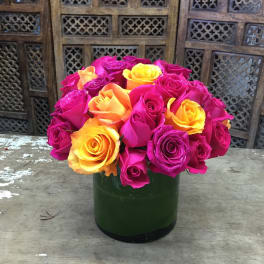 Bouquet of pink, yellow, and orange roses in a green vase