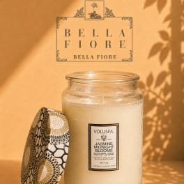 Glass jar candle with a patterned lid on a warm beige background