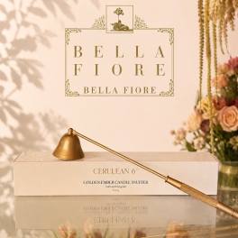 Gold candle snuffer on a box with a floral backdrop