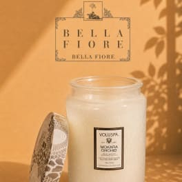 A white scented candle in a glass jar with a patterned lid