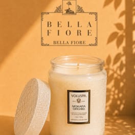 A scented candle in a textured glass jar with its lid beside it