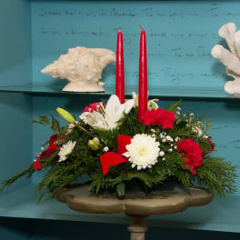 Holiday centerpiece with red candles, white lilies, and red carnations