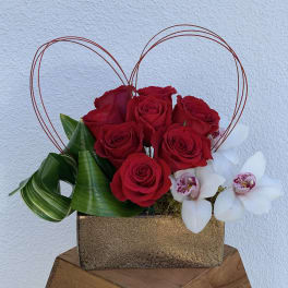 Red roses and white orchids in a gold box with wire heart handles