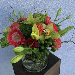 Mixed bouquet with lilies, gerbera daisies, roses, and orchids in a glass vase