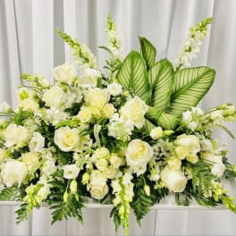 White floral casket spray with roses and snapdragons