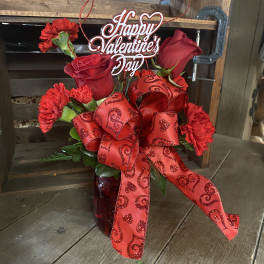 Red roses and carnations in a vase with a Happy Valentine's Day sign