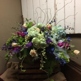 Mixed bouquet with hydrangeas, roses, and purple flowers in a wooden box