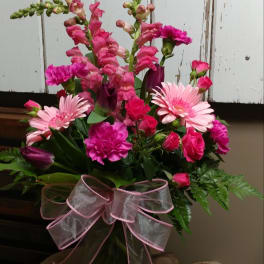 Pink mixed flower bouquet in a glass vase with a sheer ribbon bow