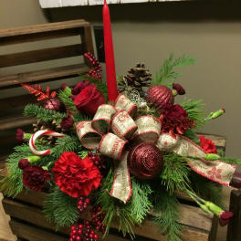 Christmas centerpiece with red flowers, pinecones, and a tall red candle