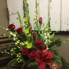 Red roses and green snapdragons in a low arrangement with a red ribbon