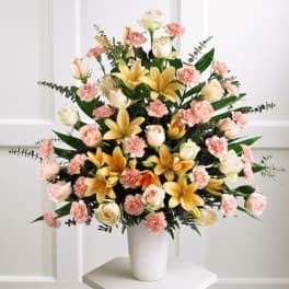 Large bouquet of peach roses, carnations, and lilies in a white vase