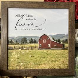 Framed farm sign with a red barn and red roses behind it