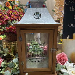 Wooden memorial lantern surrounded by pink and white flowers