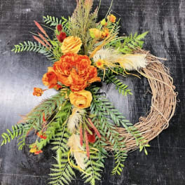 Orange floral wreath with a grapevine base and mixed greenery