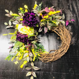 Floral wreath with purple, yellow, and white blooms on a twig base