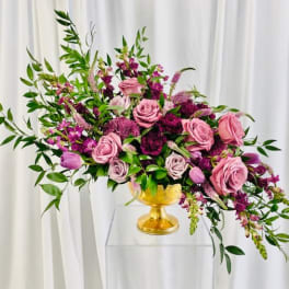 Pink and purple rose arrangement in a gold vase