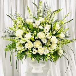 Large white floral arrangement in a pedestal vase