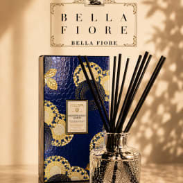 Reed diffuser in a clear glass bottle with a decorative blue box