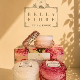 Stacked scented candles in pink and white glass jars with floral packaging