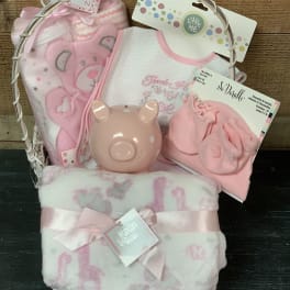 Pink baby gift basket with blankets, bibs, and a piggy bank