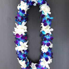 A purple, blue, and white flower lei on a dark background