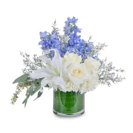 White lilies and roses in a glass vase with blue flowers