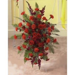Tall arrangement of red roses and carnations with fern-like greenery