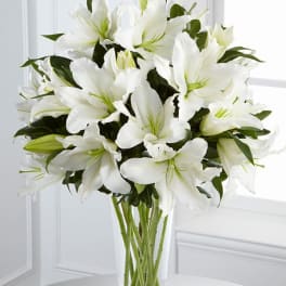 Tall arrangement of white lilies in a clear glass vase