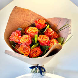 Bouquet of orange and pink roses wrapped in brown paper