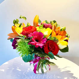 Colorful bouquet of roses, gerbera daisies, and lilies in a glass vase