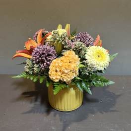 Mixed bouquet in a yellow ribbed vase with orange lilies and yellow blooms
