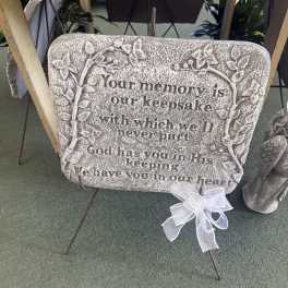 Memorial stone plaque with a white ribbon bow on a metal stand